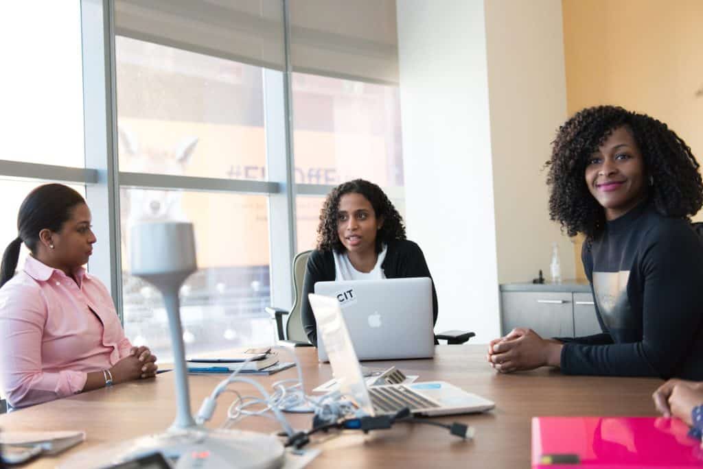 Three people sit around a table with computers around them.